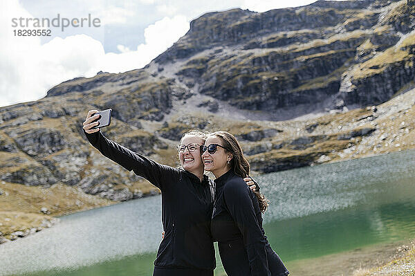 Glückliche Wanderer machen Selfie mit dem Smartphone in der Nähe des Sees