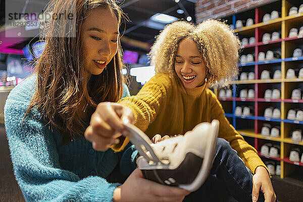 Happy woman with friend looking at bowling shoes