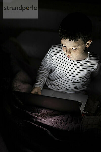 Junge schaut sich zu Hause einen Film auf dem Laptop an