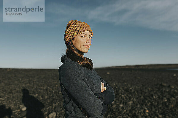 Confident woman in knit hat standing at beach on sunny day  Janubio Beach  Lanzarote  Canary Islands  Spain