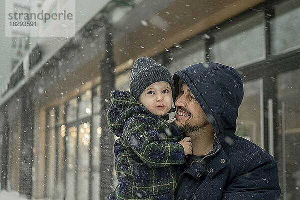 Glücklicher Vater mit Sohn  der den Schneefall genießt