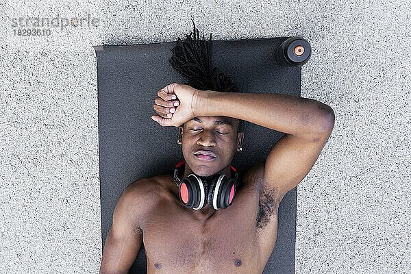 Shirtless man resting on exercise mat