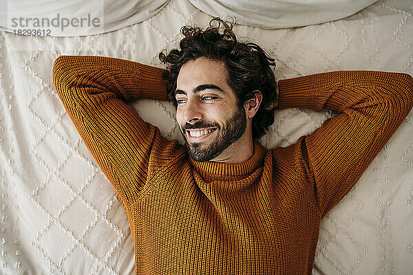 Happy young man relaxing on bed at home