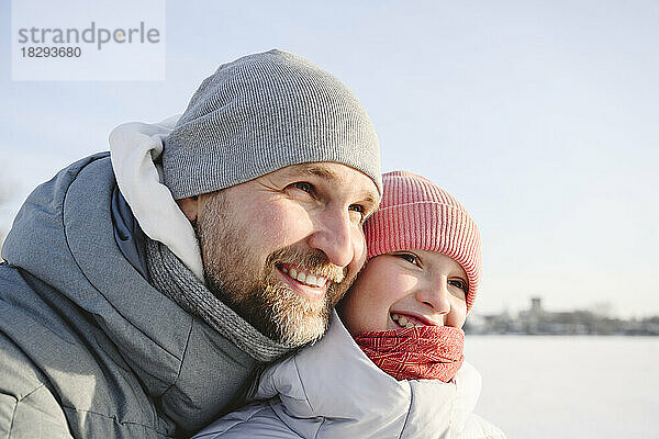Glücklicher Vater und Tochter tragen im Winter Strickmützen