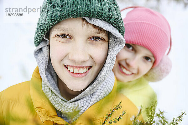 Glücklicher Bruder und Schwester mit Strickmützen im Schnee