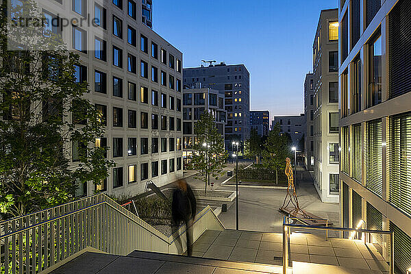 Deutschland  Bayern  München  Fußgänger steigen in der Abenddämmerung Treppen hinauf  im Hintergrund Wohnungen und Bürogebäude