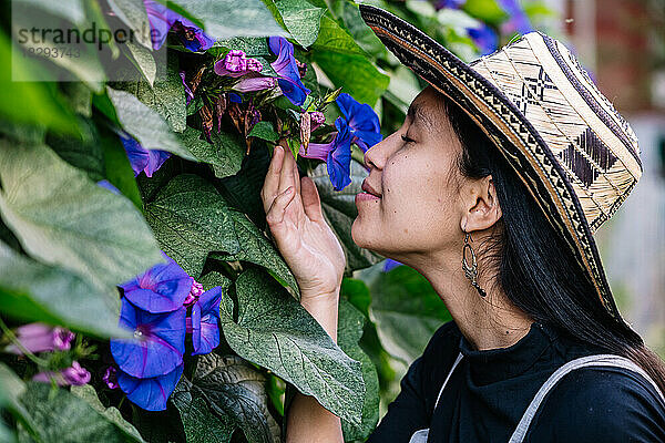 Lächelnde Frau riecht Blumen im Garten