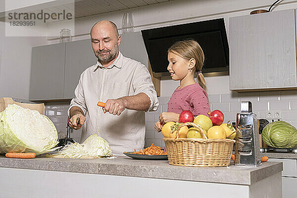 Vater und Tochter bereiten zu Hause in der Küche gesunde Mahlzeiten zu