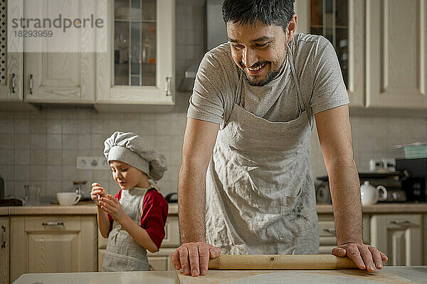 Lächelnder Vater mit Nudelholz von Sohn in der heimischen Küche
