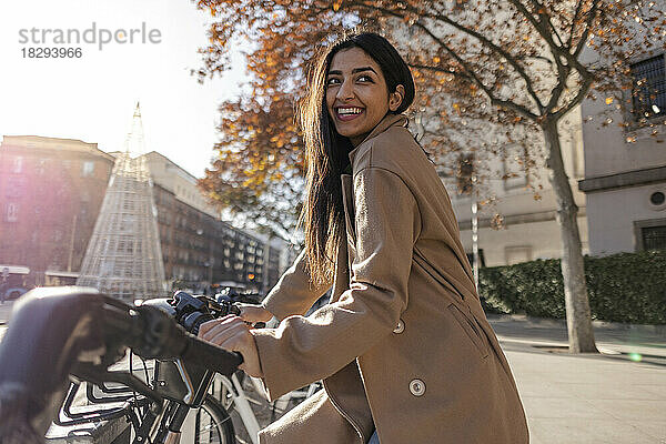 Lächelnde junge Frau  die an einem sonnigen Tag ein Fahrrad mietet
