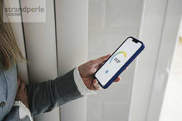 Hand einer Frau  die die Hausautomations-App auf dem Smartphone nutzt