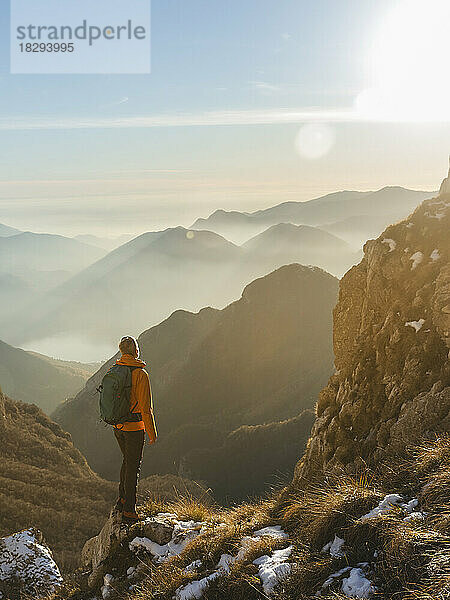 Reifer Wanderer mit Rucksack steht auf dem Berg