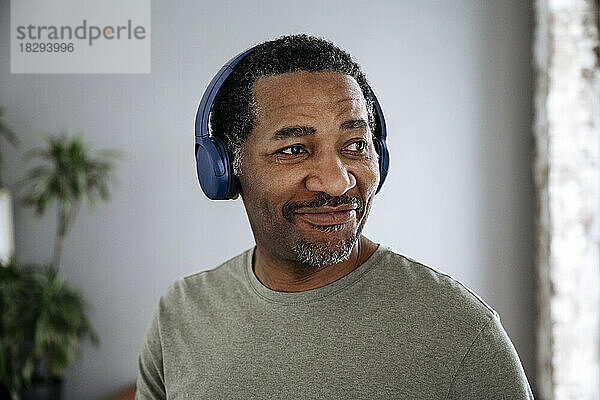 Lächelnder Mann  der über drahtlose Kopfhörer Musik hört