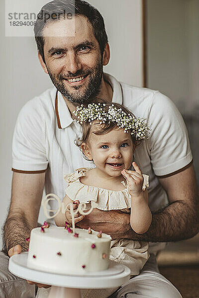 Glücklicher Vater und Tochter mit Geburtstagstorte zu Hause