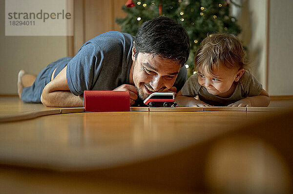 Glücklicher Vater und Sohn spielen zu Hause mit der Spielzeugeisenbahn