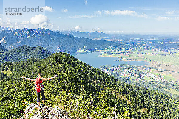 Germany  Bavaria  Kochel am See  Female hiker standing on mountaintop with Kochelsee lake in background