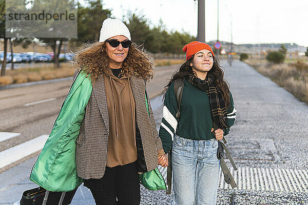 Glückliche Mutter und Tochter gehen Händchen haltend auf der Straße
