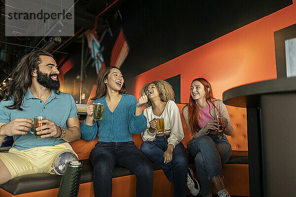 Gemischtrassige Freunde trinken Bier auf dem Sofa in der Bowlingbahn