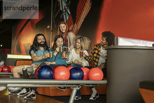 Gemischtrassige Freunde trinken Bier auf dem Sofa in der Bowlingbahn