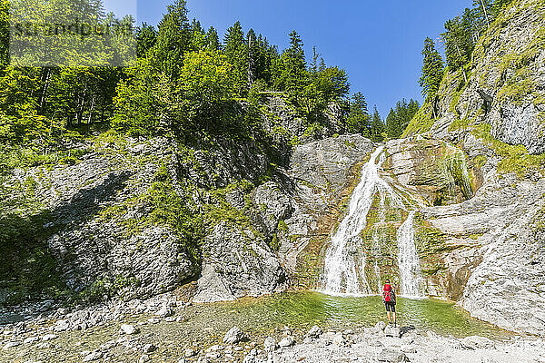 Germany  Bavaria  Female hiker admiring Glasbachwasserfall in summer