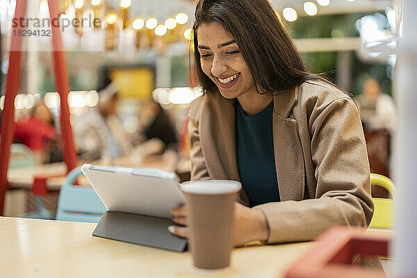 Glückliche Frau sitzt im Café und benutzt Tablet-PC