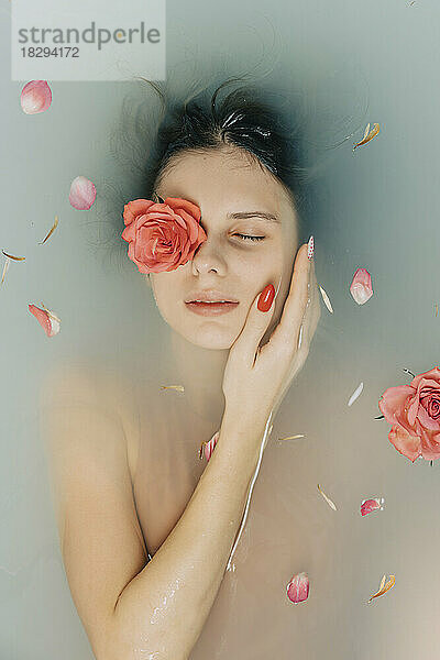 Girl taking bath with roses in bathtub