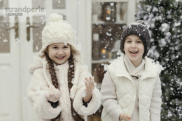 Glücklicher Bruder und Schwester genießen den Schnee im Vorgarten