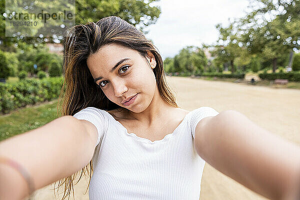 Schöne junge Frau macht Selfie im Park