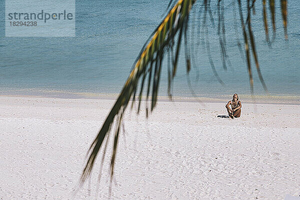 Frau sitzt am Ufer am Strand