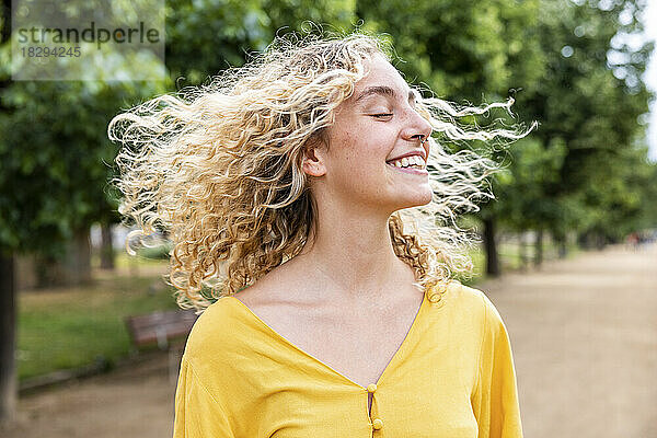 Glückliche junge Frau mit blonden Haaren genießt den Park