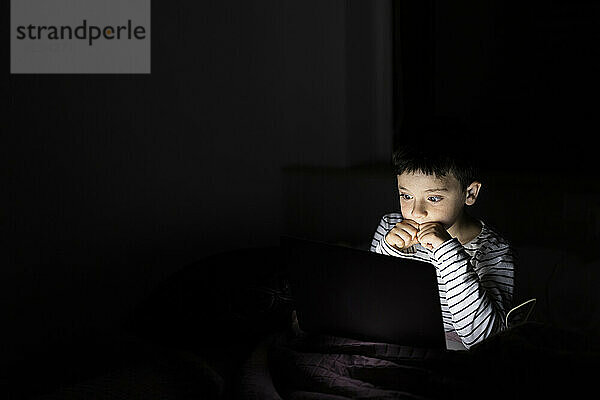 Junge schaut sich zu Hause einen Gruselfilm auf dem Laptop an
