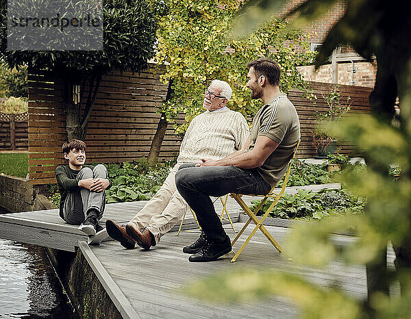 Father  son and grandson sitting at garden pond talking and relaxing