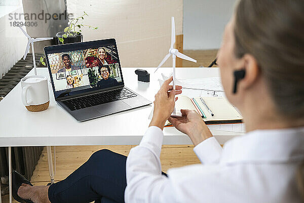 Geschäftsfrau zeigt Windkraftanlage bei Videokonferenz im Büro