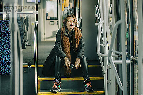 Reife Frau sitzt auf Stufen in der Straßenbahn