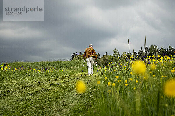 Älterer Mann läuft auf einem Feldweg unter dem Himmel