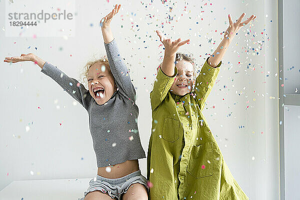 Girls having fun throwing confetti at home