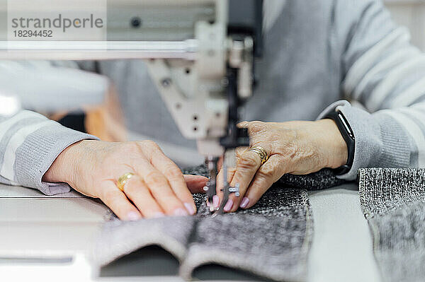 Senior craftswoman using sewing machine in workshop