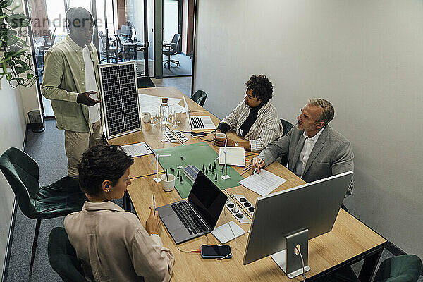 Junger Geschäftsmann diskutiert mit Kollegen über Solarpanel
