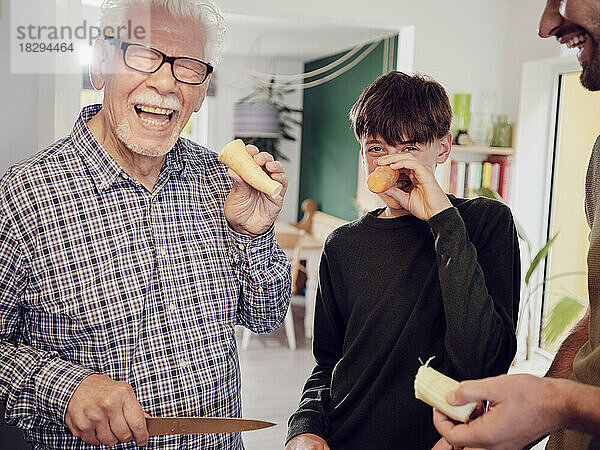 Großvater und Enkel in der Küche amüsieren sich mit Karotten