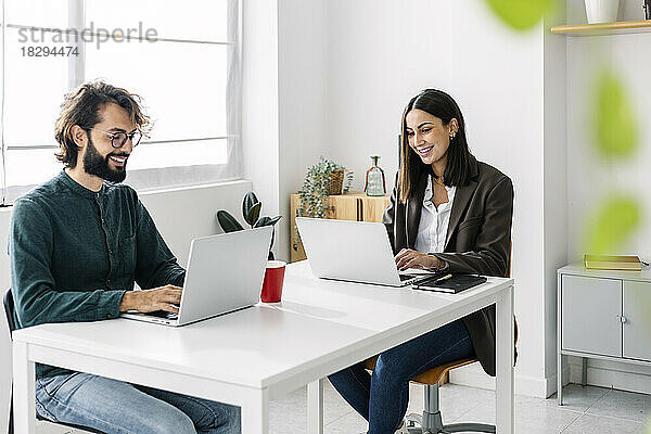 Zufriedene Geschäftskollegen nutzen Laptop am Schreibtisch im Büro