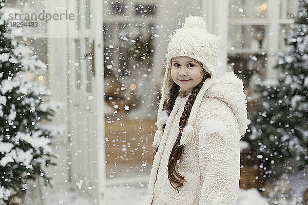 Lächelndes Mädchen mit geflochtenen Haaren  das im Schnee steht