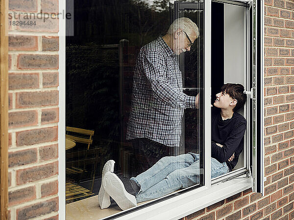 Großvater und Enkel schauen sich zu Hause am Fenster an