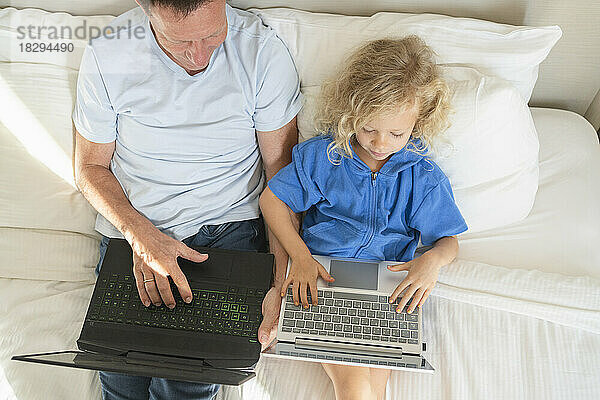 Mädchen und Mann benutzen Laptops zu Hause im Bett
