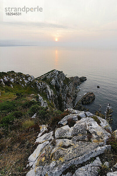 Tranquil view of rocks by sea at sunset