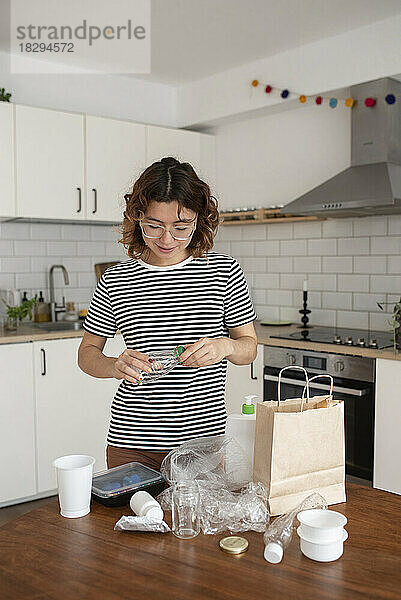 Woman recycling plastic trash in kitchen at home