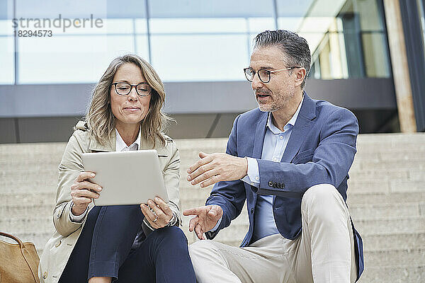Reife Geschäftsleute diskutieren mit Tablet-PC über Schritte