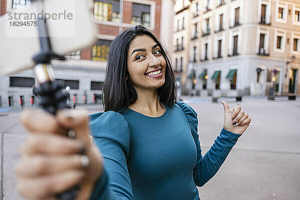 Lächelnde junge Frau  die in der Stadt ein Selfie mit dem Smartphone macht