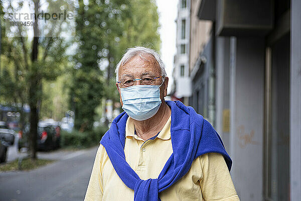 Älterer Mann trägt schützende Gesichtsmaske auf Fußweg
