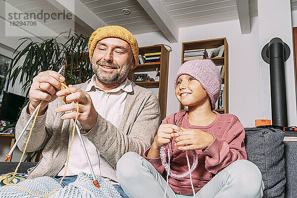 Vater und Tochter stricken zu Hause gemeinsam auf der Couch