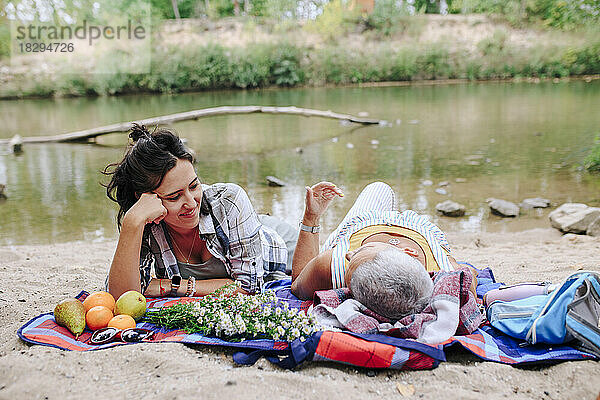 Junge Frau entspannt sich mit Freundin am Seeufer im Park